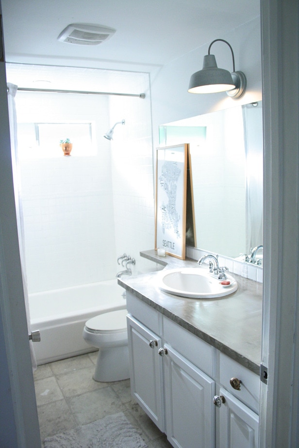 Concrete counters, painted shower tile, barn light, white cabinets