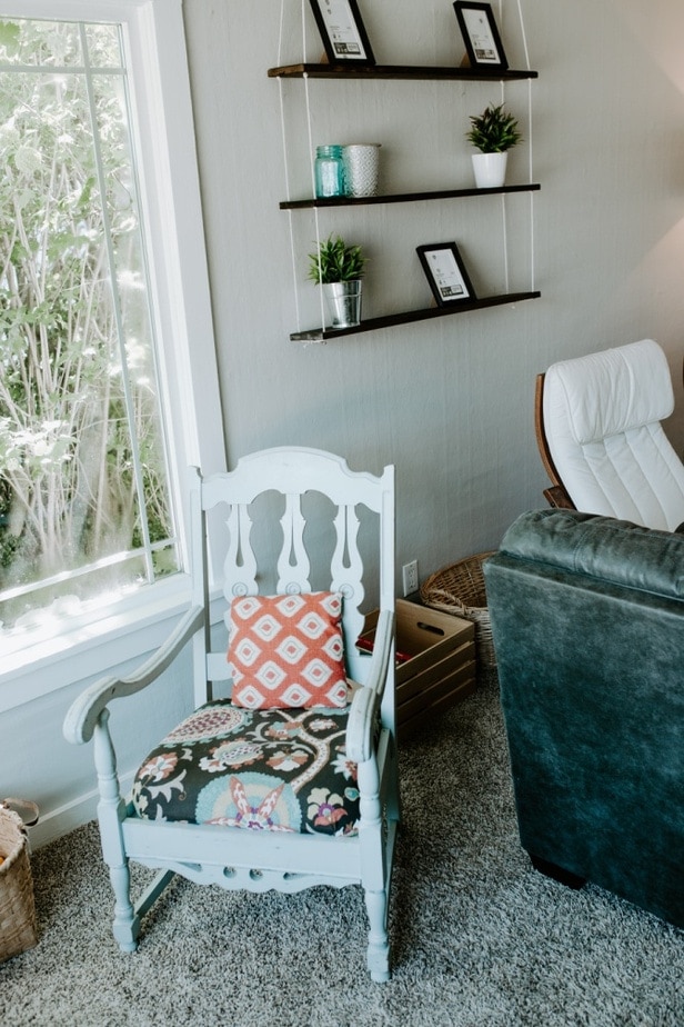 living room corner with rustic chair and hanging rope shelf