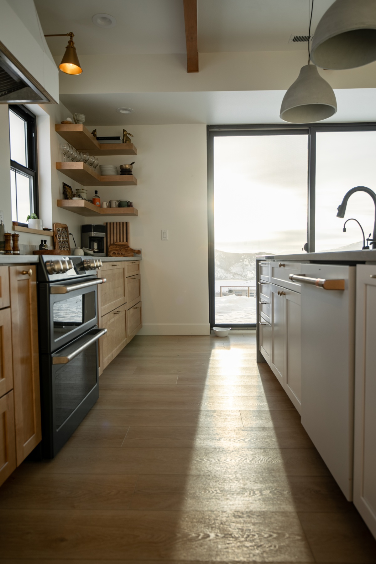 kitchen view with cafe appliances, concrete pendants, and big sliding door.
